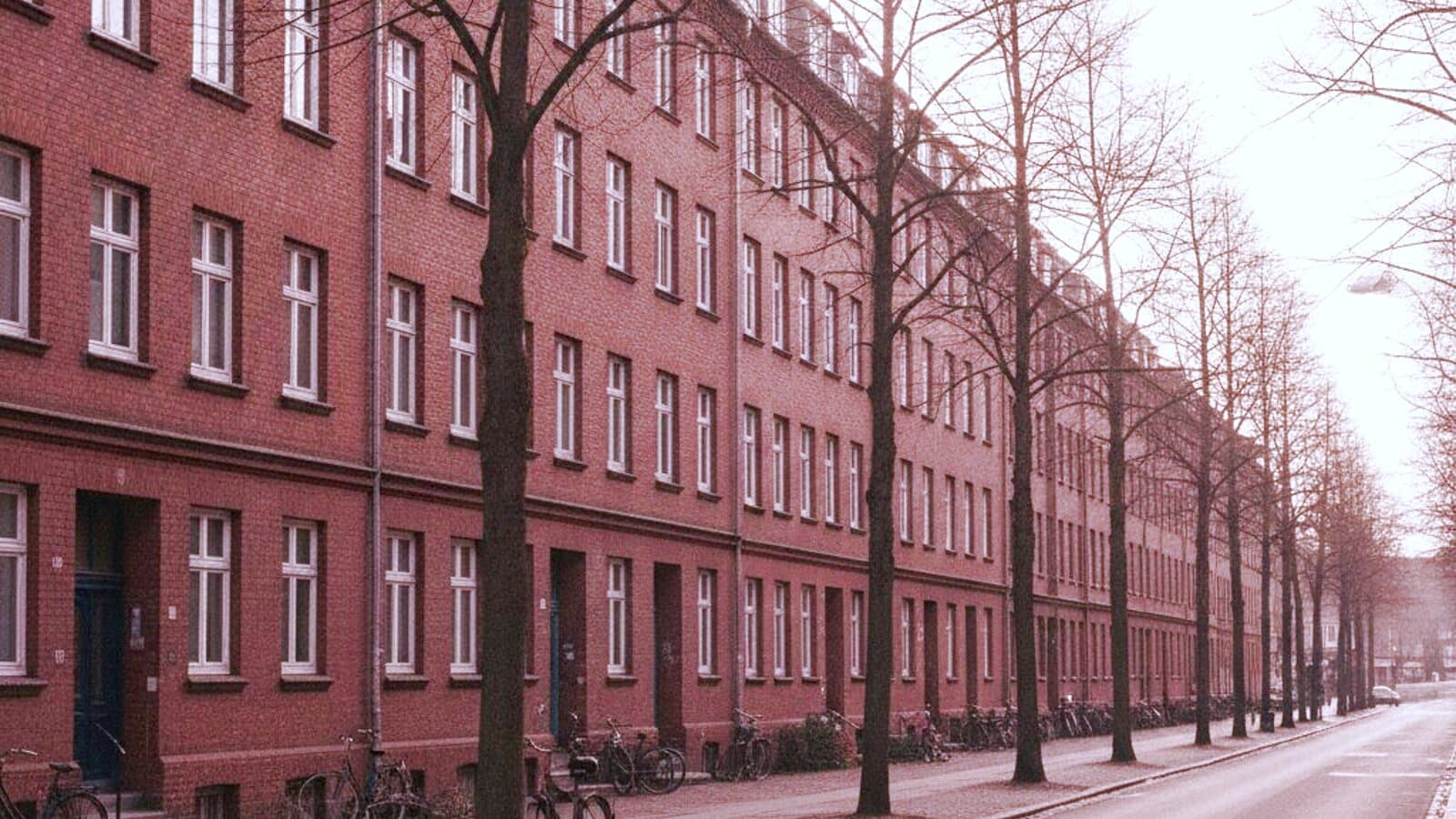 Wohnstraße mit Backsteinhäusern aus der Gründerzeit bei bedecktem Himmel