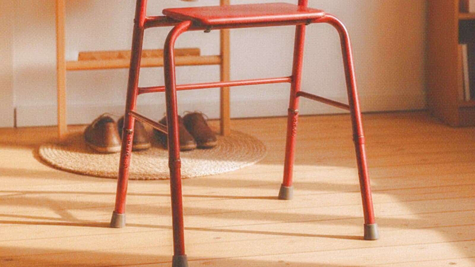 Rollator im sonnigen Flur einer Wohnung, daneben ein Paar Schuhe