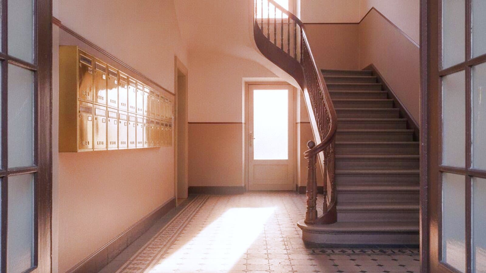 Treppenhaus eines Altbaus mit gewundenem Handlauf und Licht vom Treppenfenster